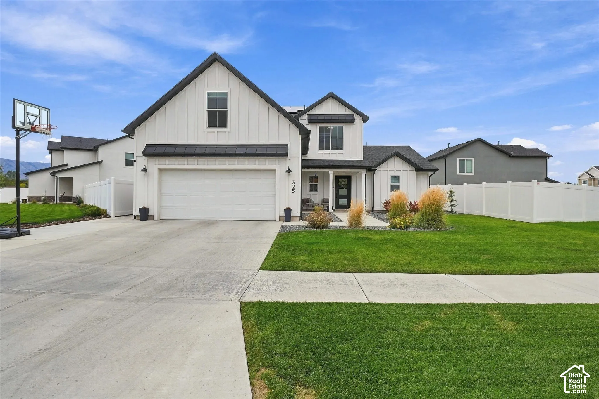 Modern farmhouse architecture featuring a white board-and-batten exterior, black roof, and an attached two-car garage