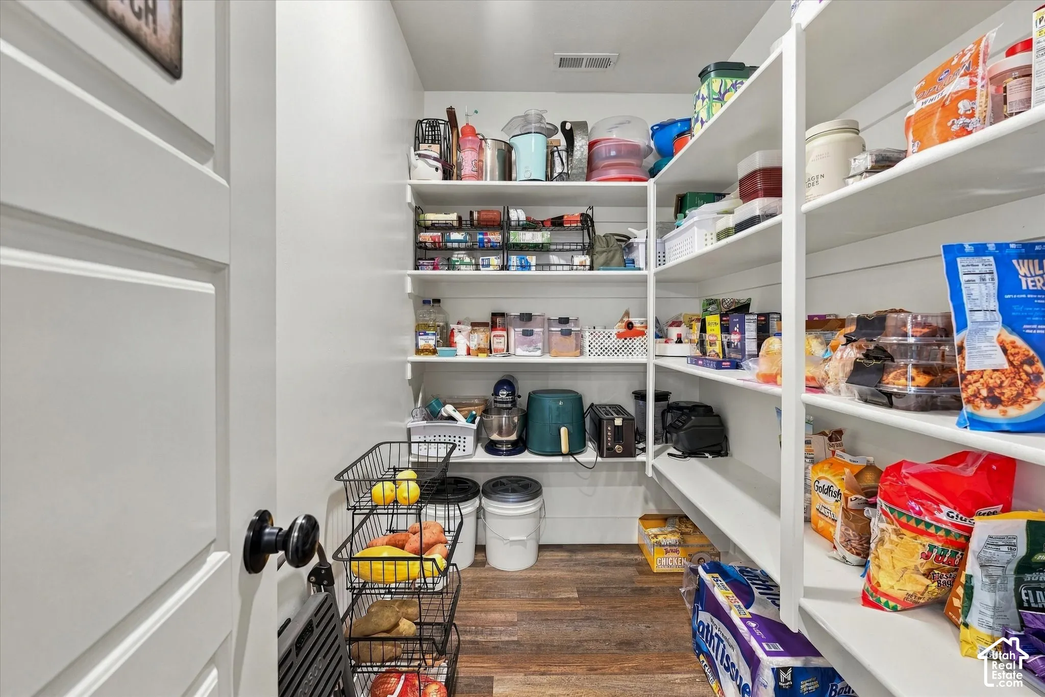 Expansive pantry featuring extensive built-in shelving, wood-finish flooring, and white painted walls
