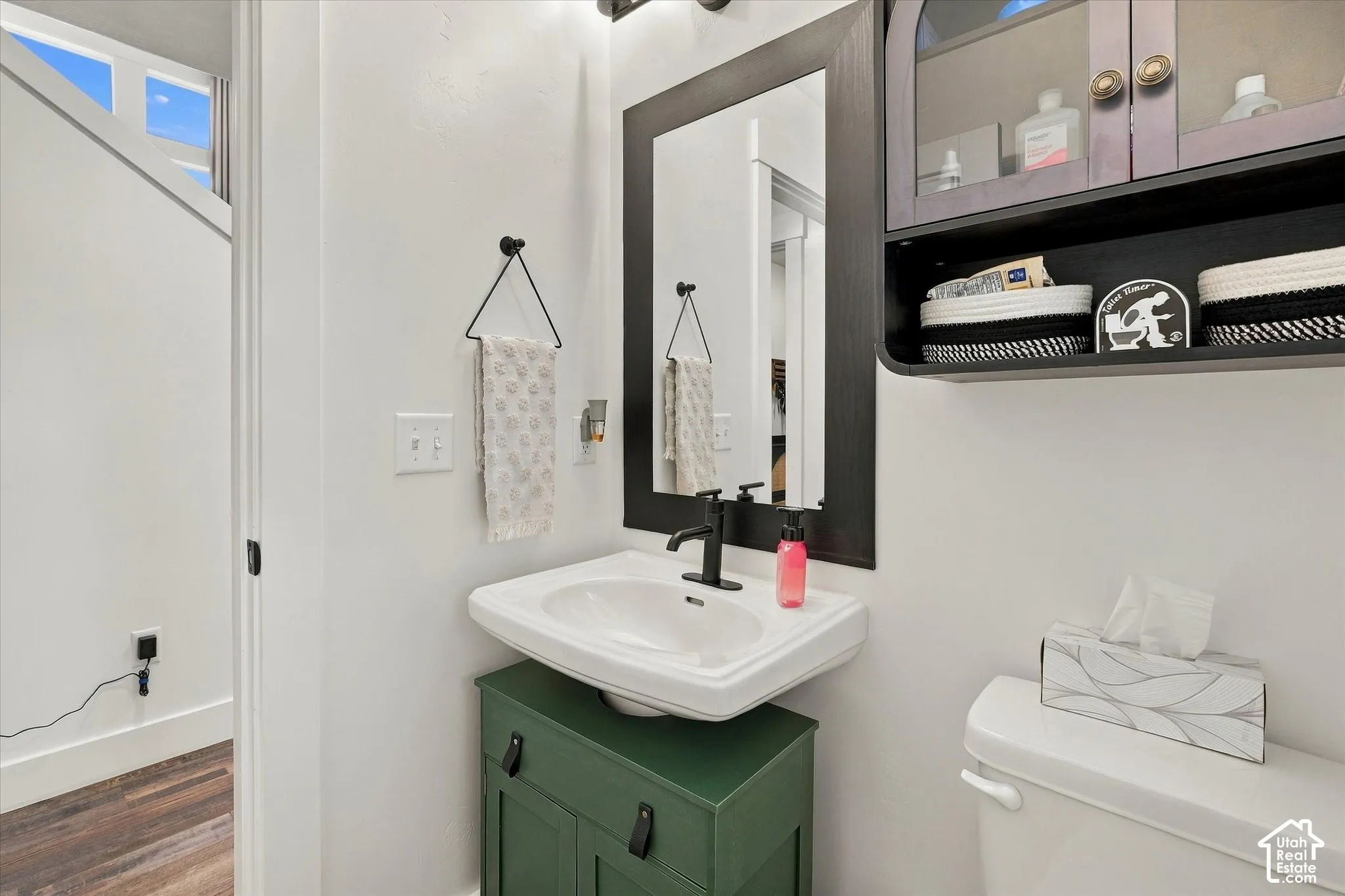 Wall-mounted sink with matte black faucet, dark framed mirror, and built-in vanity with storage