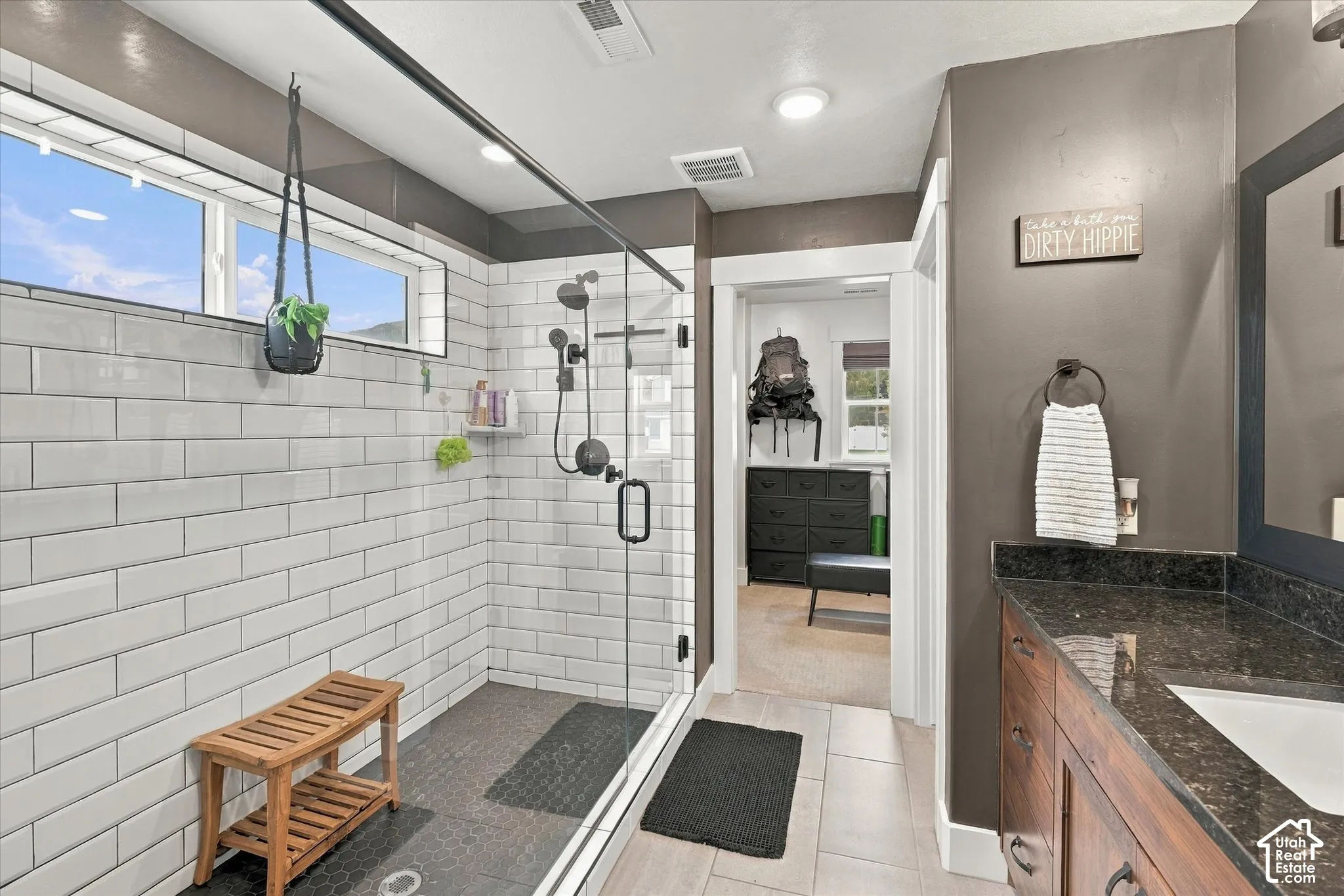 Walk-in shower with white subway tile surround, dark shower floor, and a glass enclosure