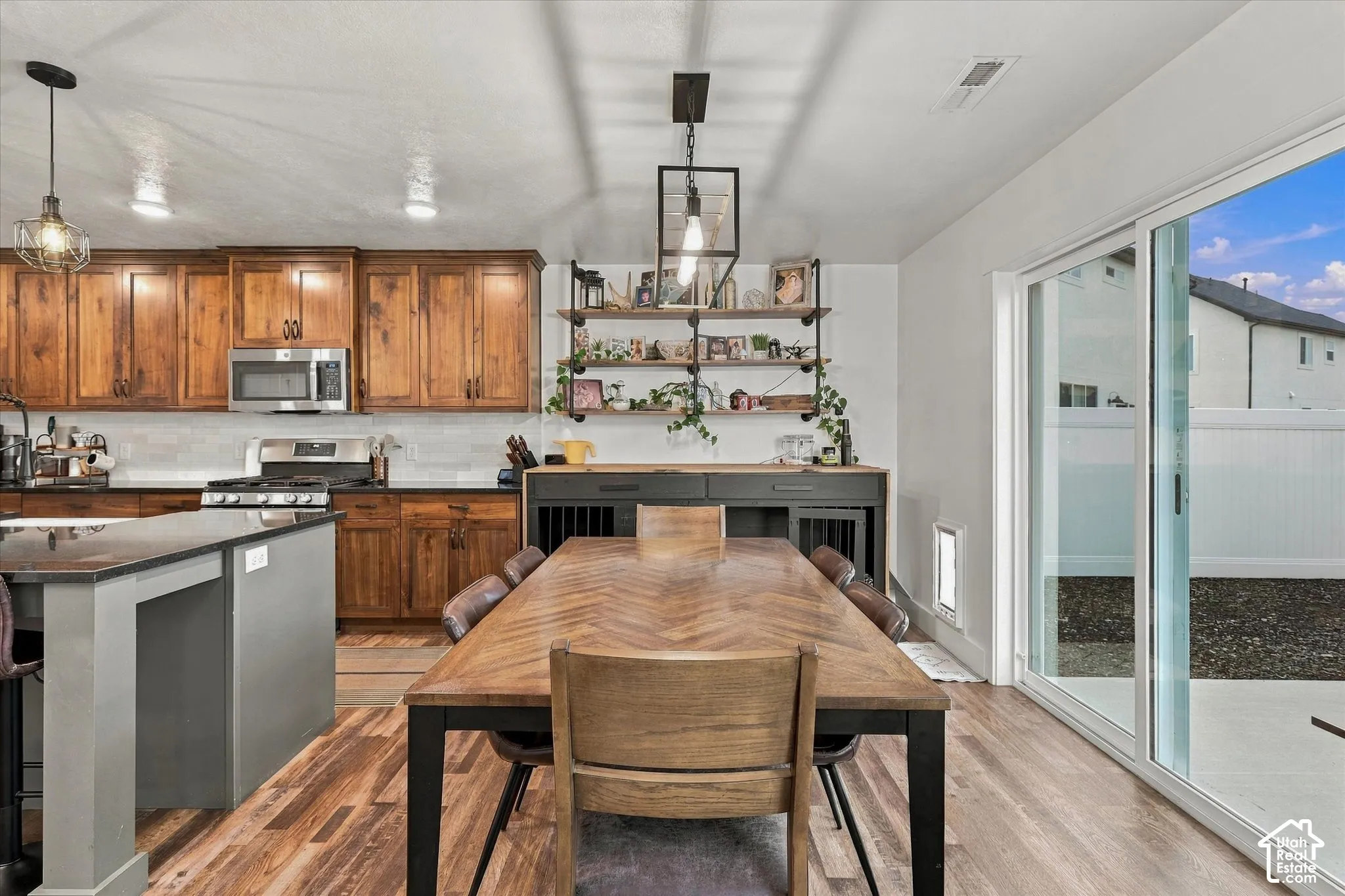 Wood-finish flooring throughout, alongside rich wood cabinetry and a kitchen island with a dark countertop