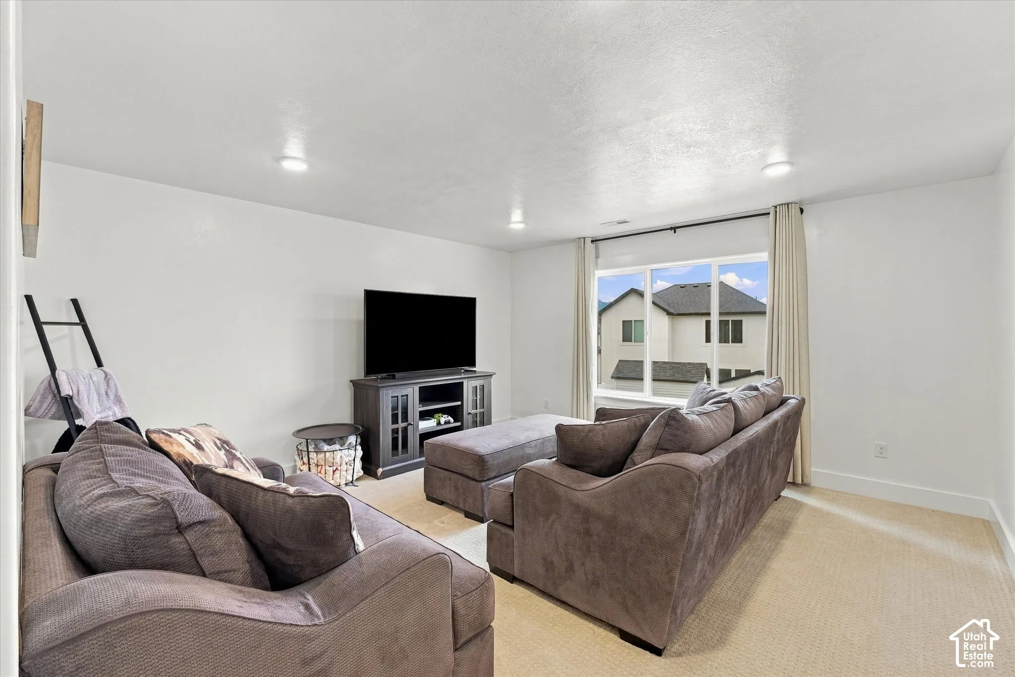 Recessed lighting, large window with ample natural light, carpeted flooring, and a media console with storage