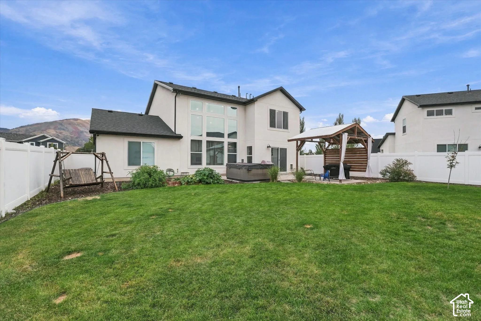 Expansive backyard featuring a manicured lawn, white privacy fencing, and a built-in pergola with a slatted privacy screen