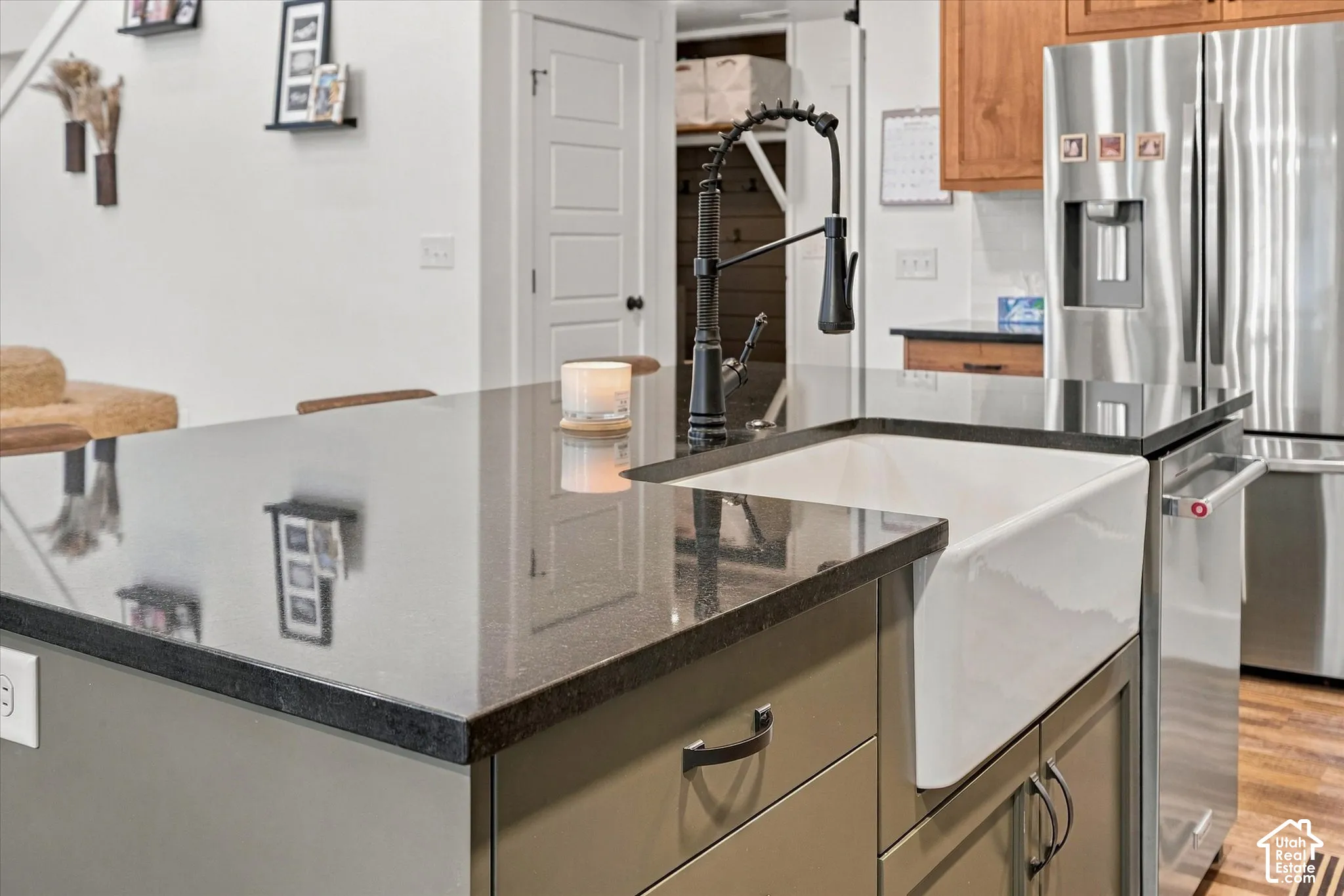 Kitchen island with dark countertop, integrated farmhouse sink, and matte black pull-down faucet