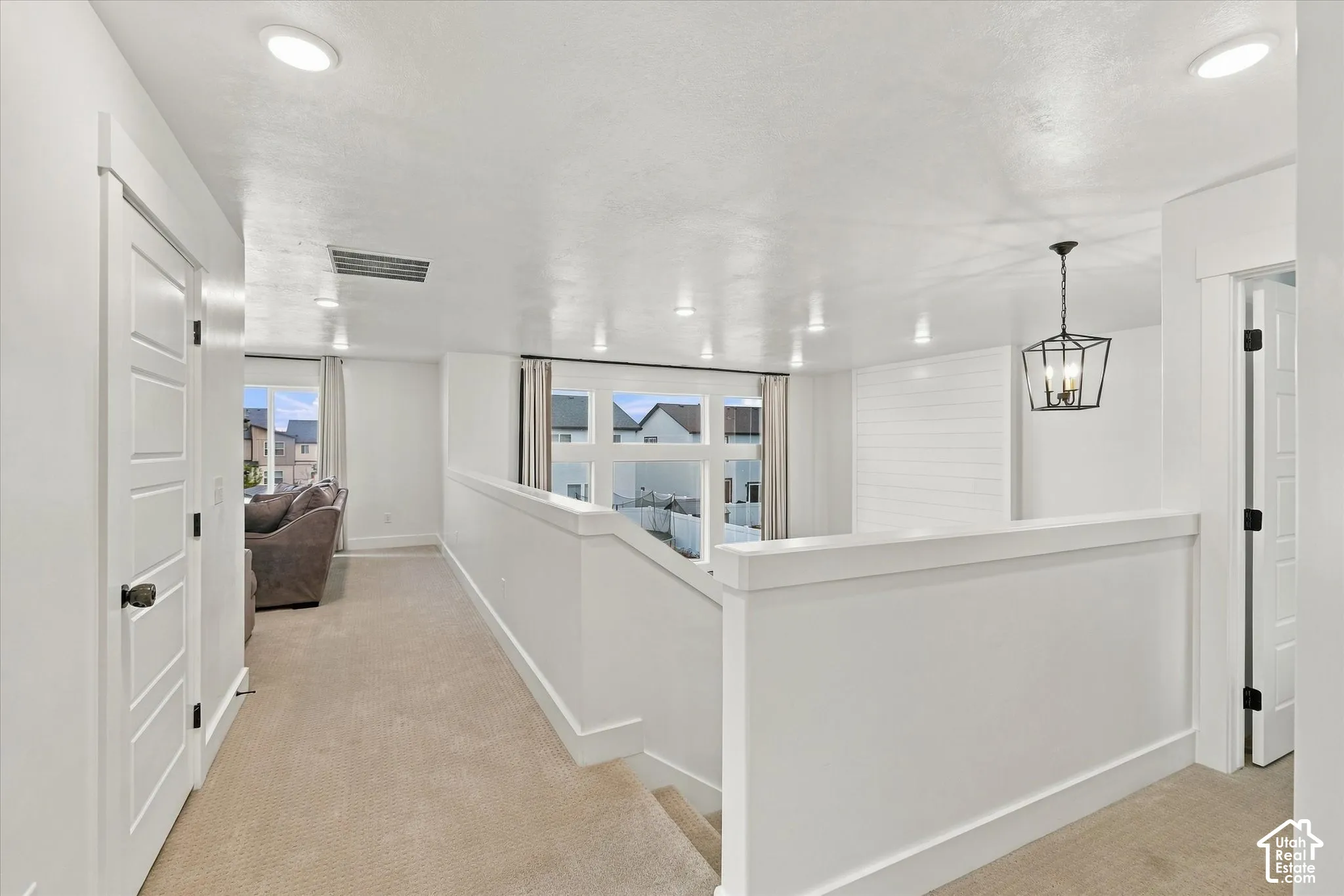Recessed ceiling lighting, white shiplap accent wall, staircase with white railing, paneled interior doors, and a black metal chandelier