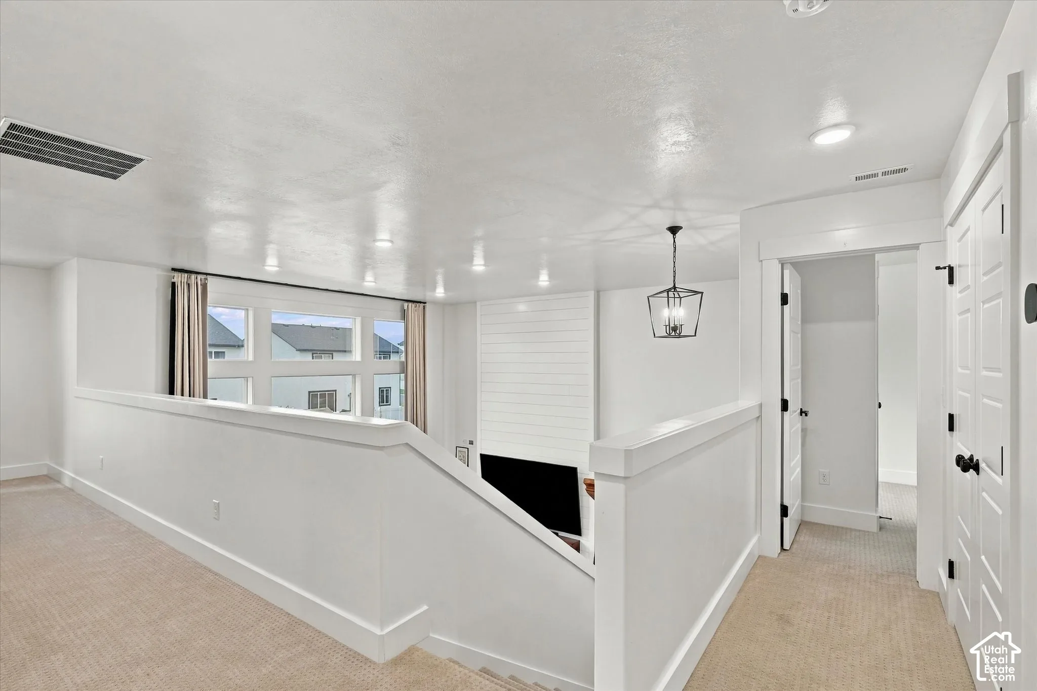 Neutral carpeted flooring, recessed ceiling lighting, a contemporary hanging light fixture, and a window with trim
