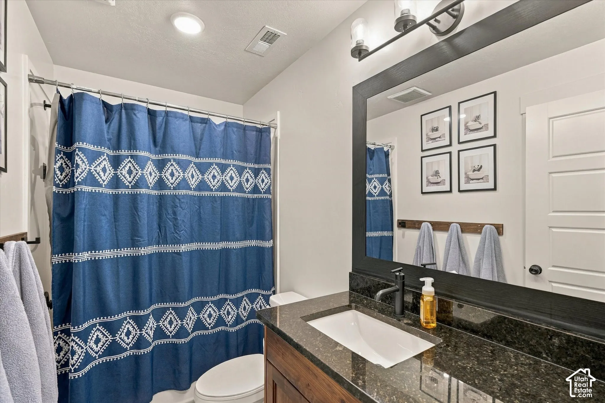 Built-in vanity with a rectangular undermount sink, dark countertop, and matte black faucet