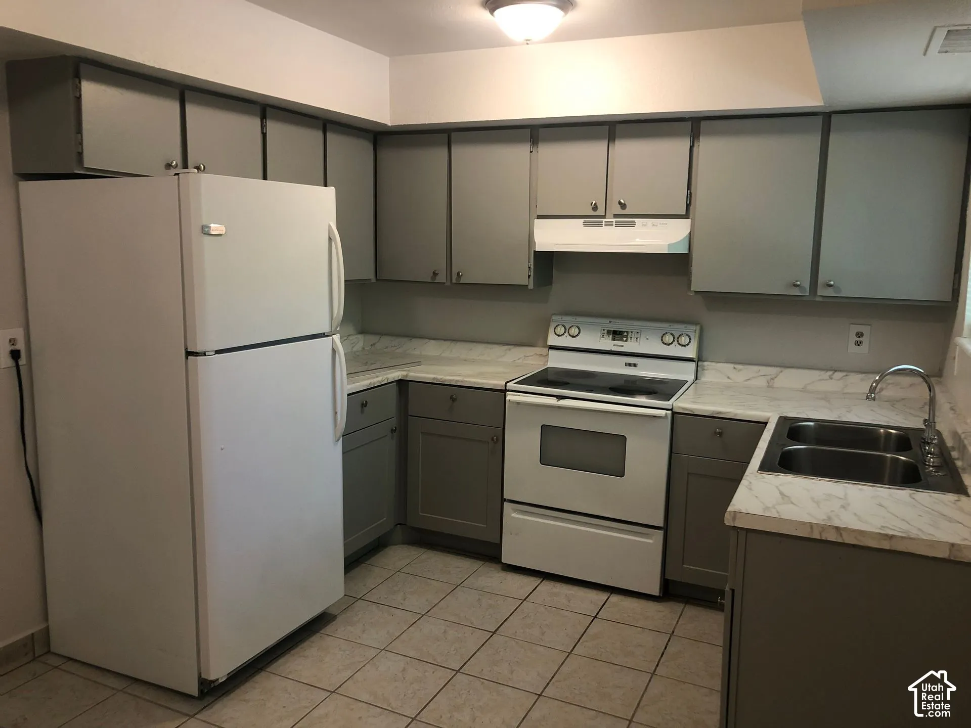Kitchen featuring gray cabinetry, light-toned countertops, a white refrigerator, and a white electric range