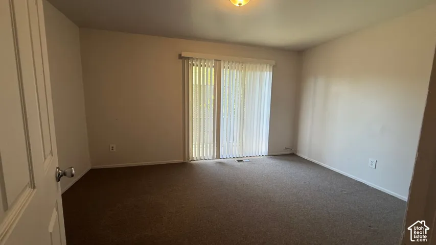 Room featuring wall-to-wall carpeting, neutral wall finishes, and a sliding glass door with vertical blinds