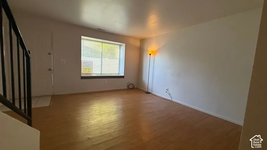 Wood-finish flooring throughout, white painted walls, and a large window with ample natural light