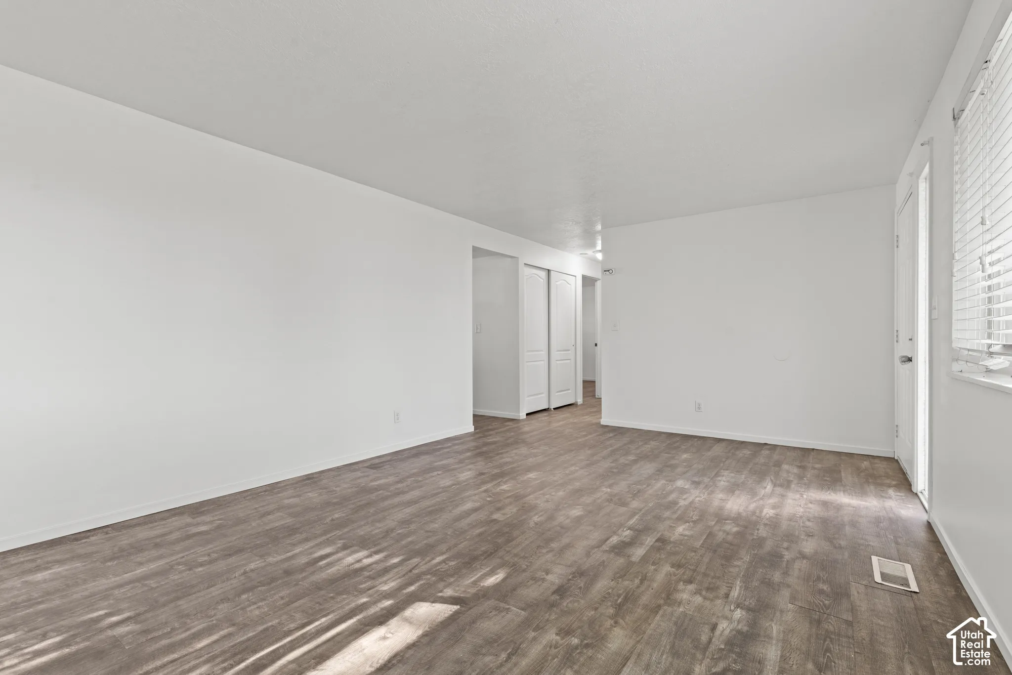 Expansive room featuring wood-finish flooring, white walls, and a white ceiling