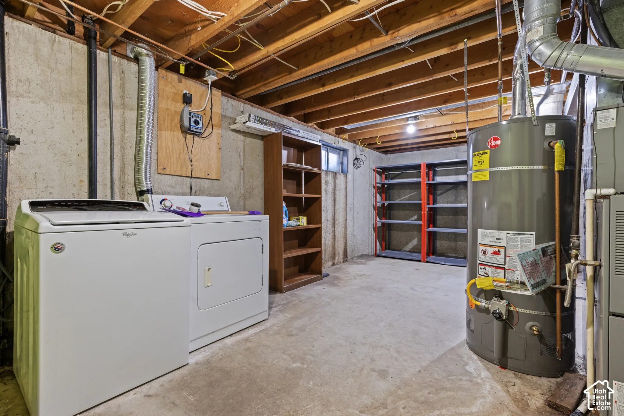 Utility area featuring a washer and dryer, exposed ceiling joists, built-in shelving, and a water heater