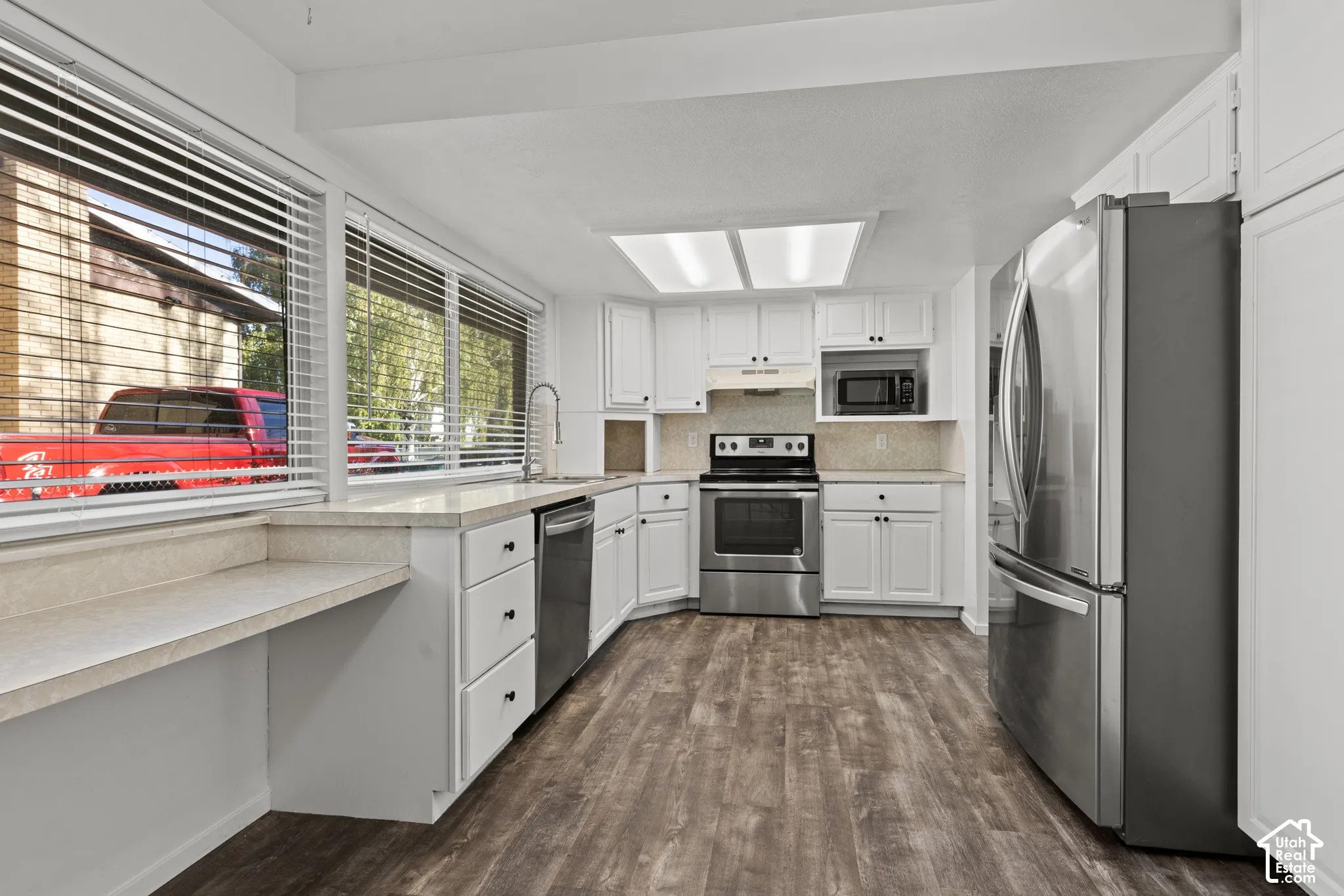 Kitchen featuring wood-finish flooring, white cabinetry, a stainless steel electric range, and a stainless steel refrigerator