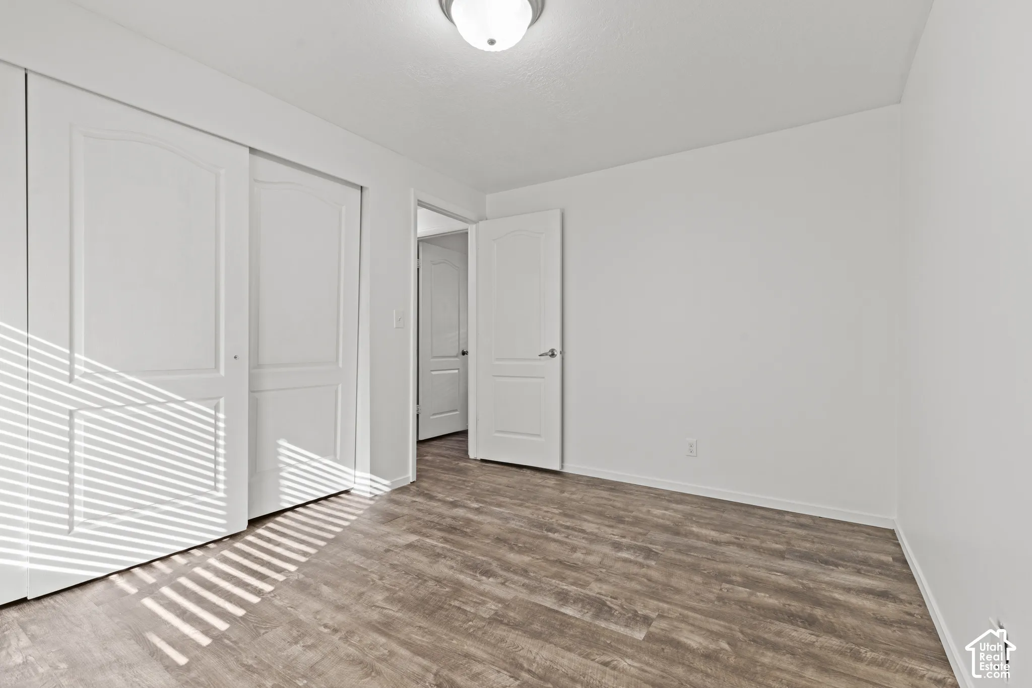 Wood-finish flooring, white walls, white trim, recessed lighting, and white panel doors