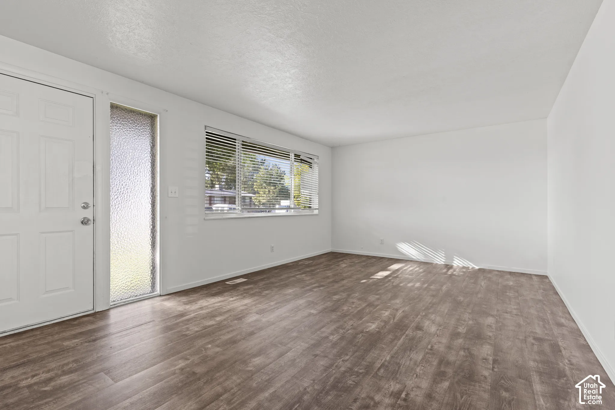 Neutral wall colors, wood-finish flooring, and multiple windows with blinds