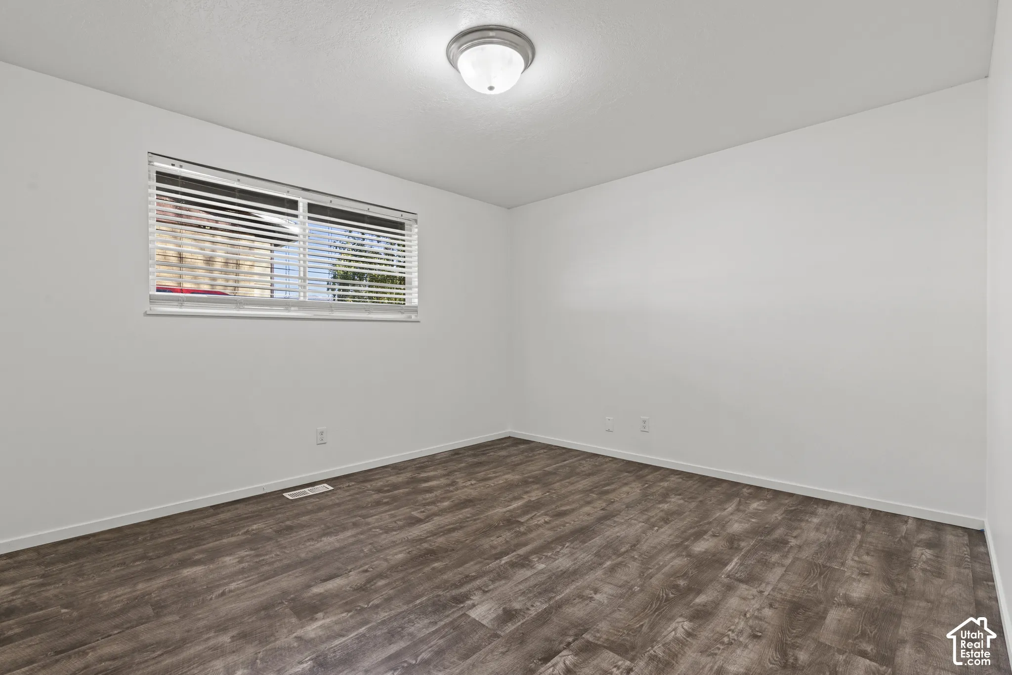 Wood-finish flooring, white walls, and a flush-mount ceiling light