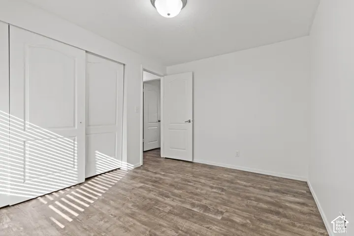 Wood-finish flooring, white walls, white trim, recessed lighting, and white panel doors