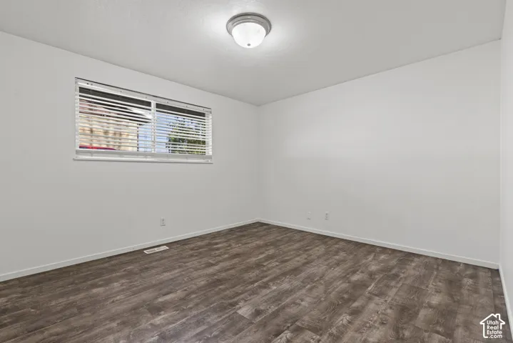Wood-finish flooring, white walls, and a flush-mount ceiling light