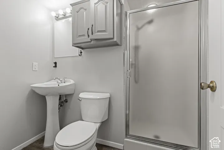 Pedestal sink with chrome fixtures, built-in medicine cabinet, and a shower with a frosted glass enclosure