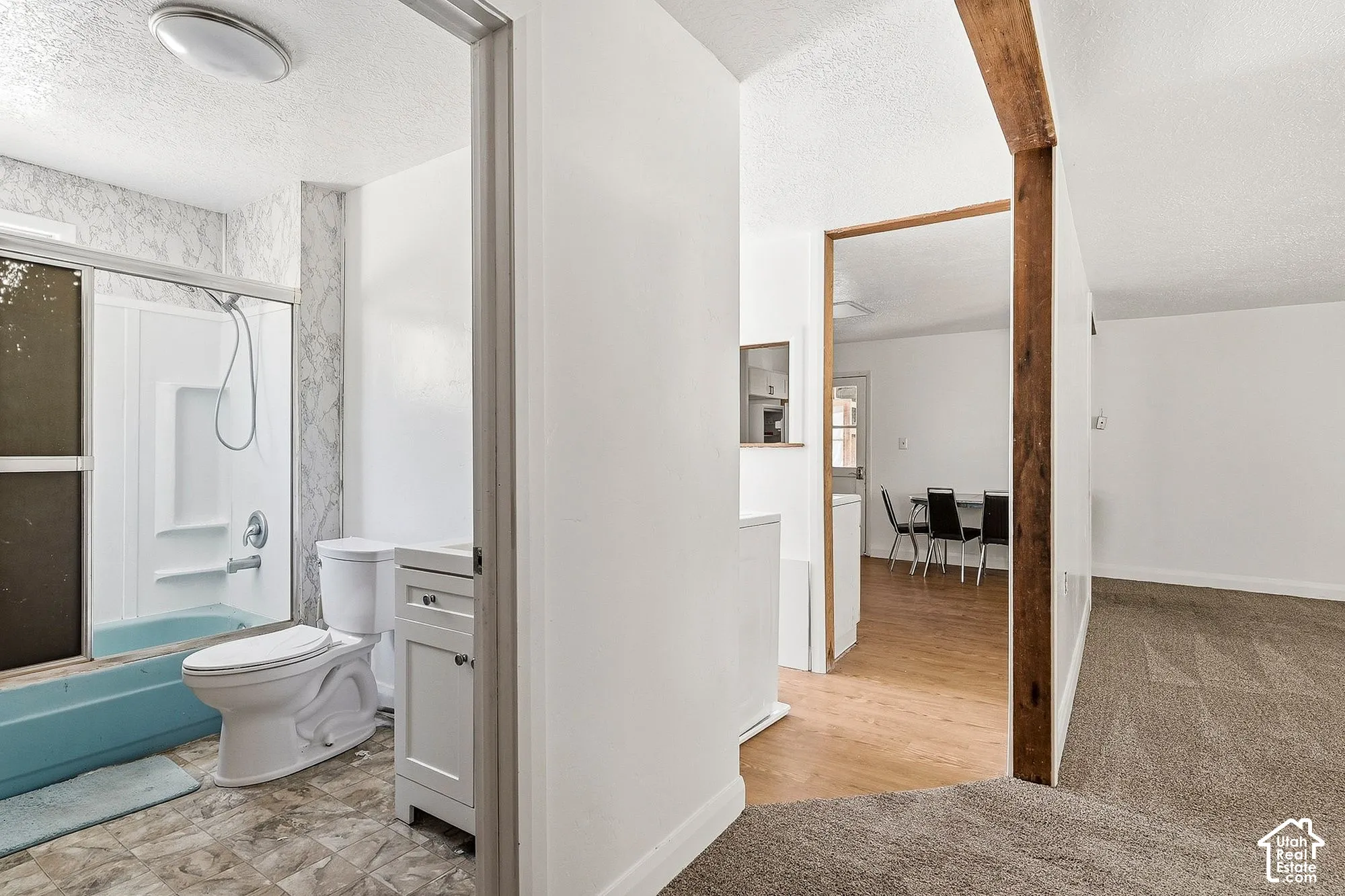 Bathroom featuring a shower/tub combination with sliding glass doors, a single vanity with storage, and a toilet