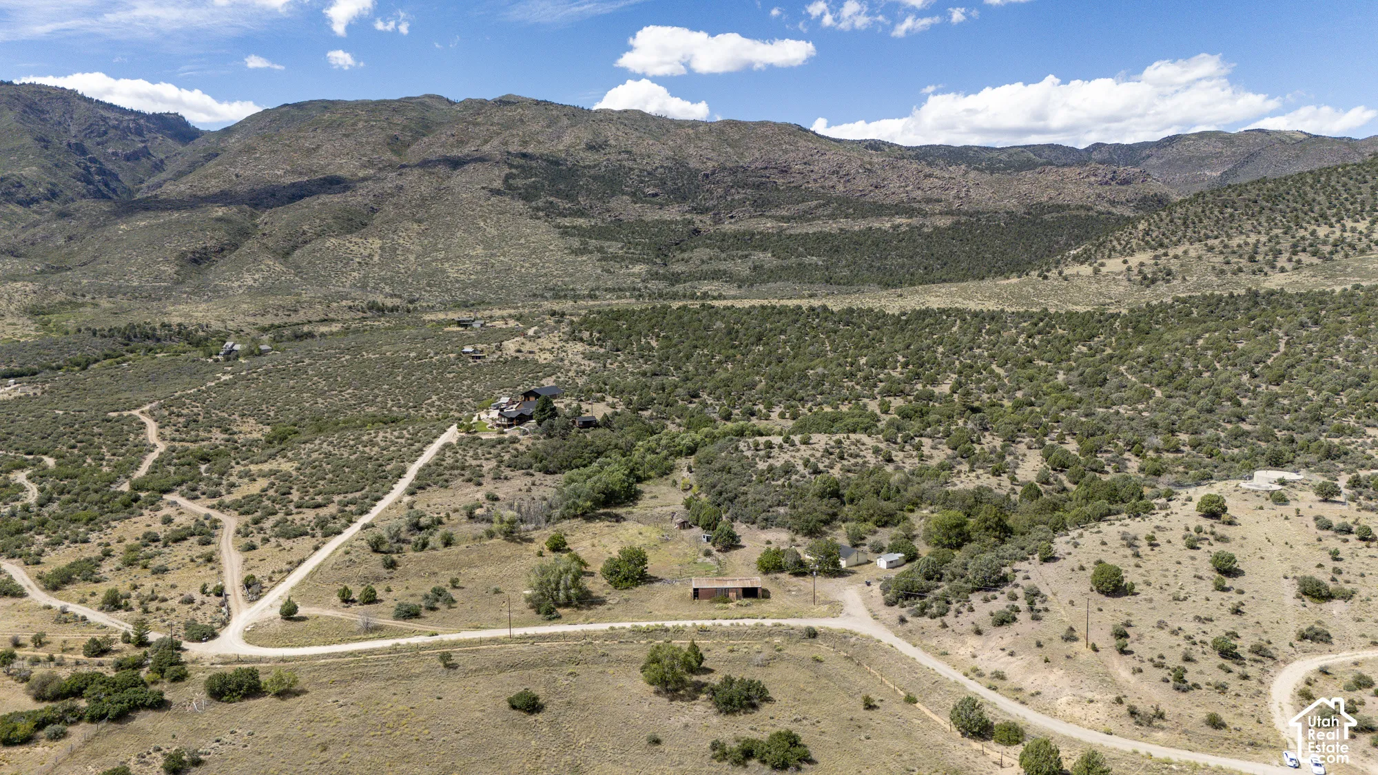 Expansive property featuring varied terrain, natural vegetation, and distant mountain backdrops