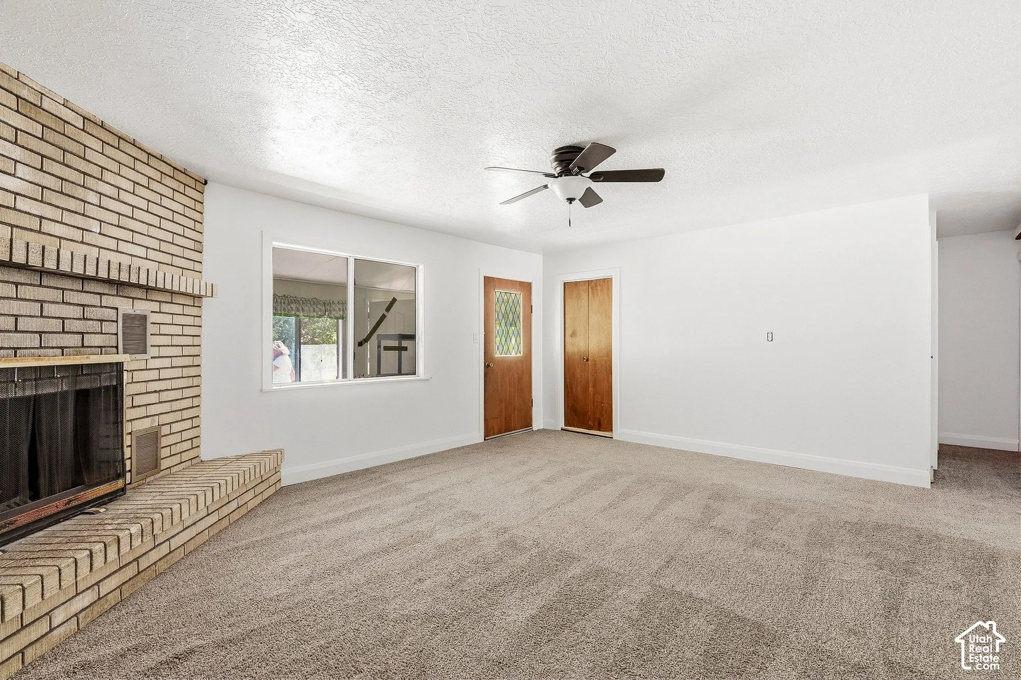 Brick fireplace with a hearth, dual pane window, and carpeted flooring
