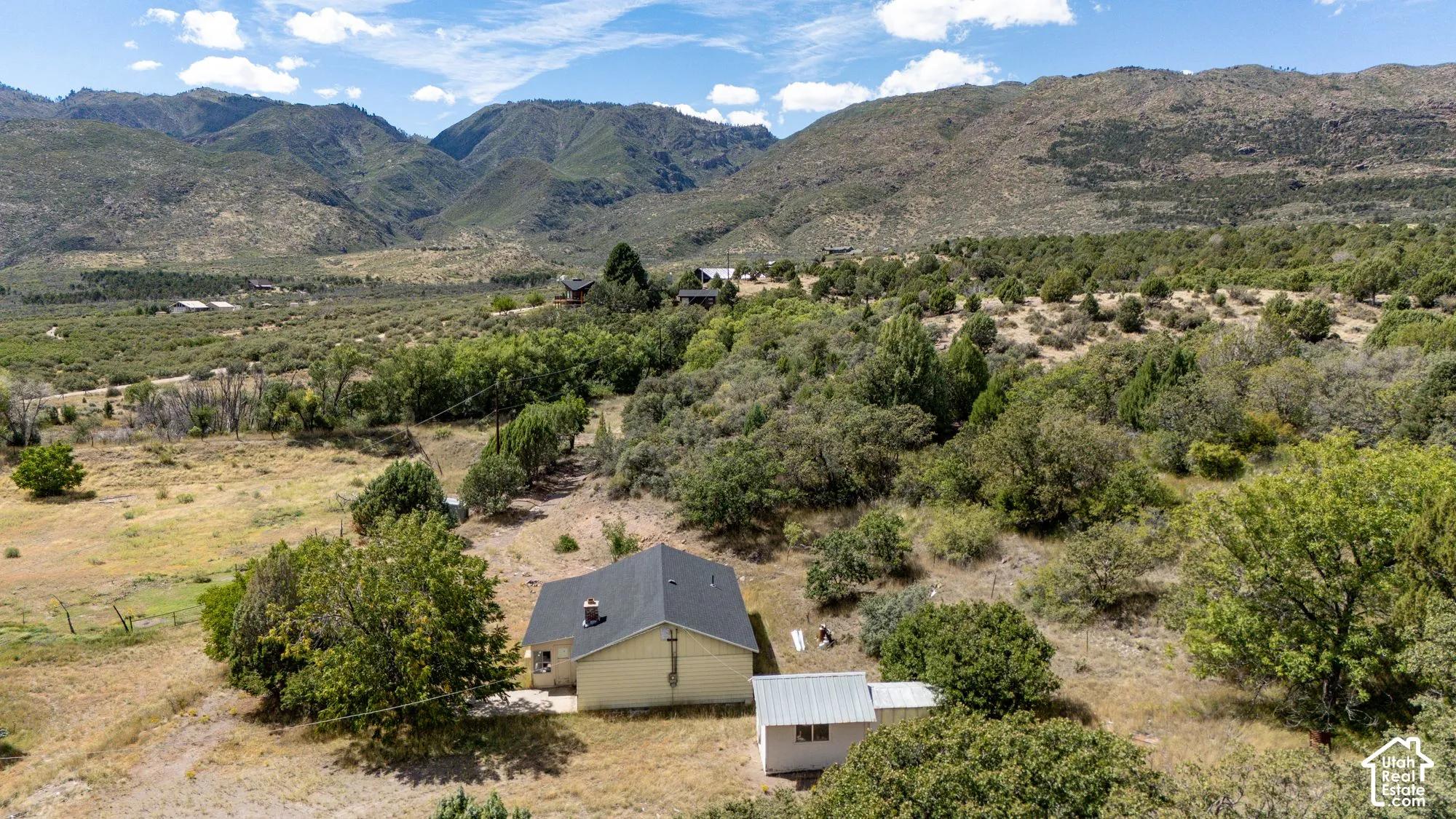 Expansive property with a detached accessory structure, surrounded by mountainous terrain and abundant natural foliage
