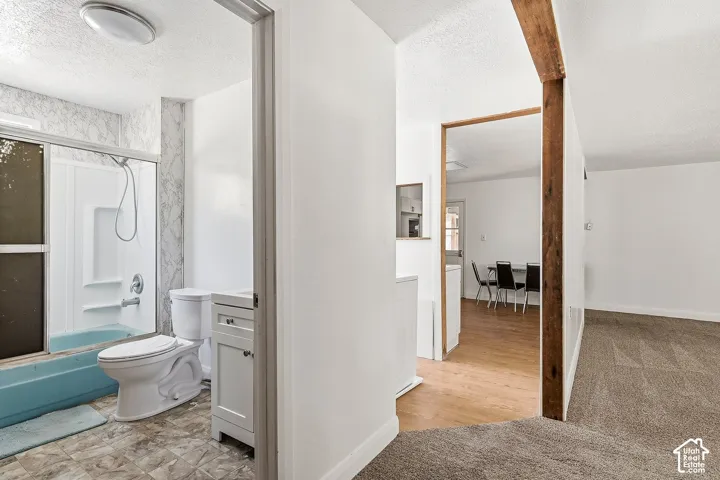 Bathroom featuring a shower/tub combination with sliding glass doors, a single vanity with storage, and a toilet