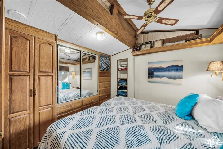 Wood-finish built-in cabinetry, mirrored closet doors, built-in shelving, ceiling fan, and wall-mounted light fixture