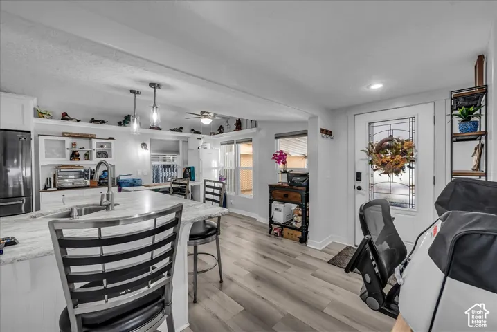 Kitchen island with integrated sink, stainless steel appliances, recessed lighting, wood-finish flooring, and a white paneled entry door