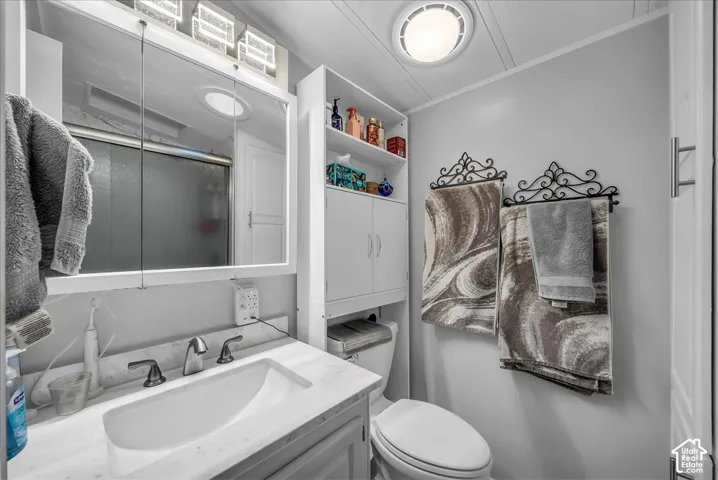 Vanity with a white basin and stone countertop, mirrored medicine cabinet, and wall-mounted storage cabinetry