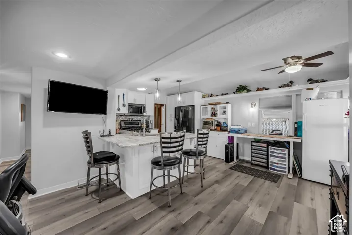 Kitchen featuring an island with stone countertop, white cabinetry, integrated stainless steel appliances, and wood-finish flooring