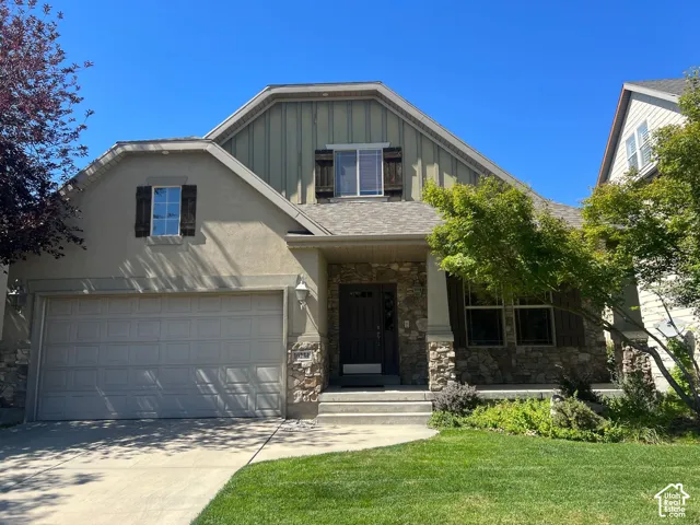 Stucco exterior with stone accents, attached two-car garage, and a covered entryway