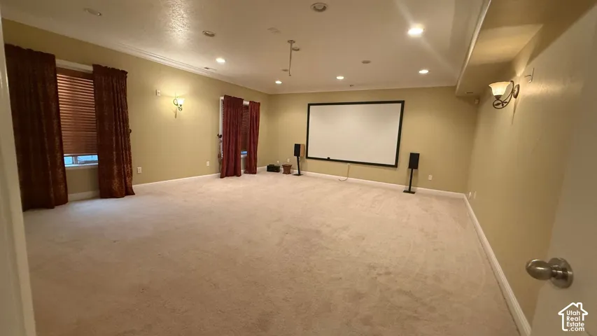 Recessed lighting, wall sconces, wall-mounted screen, and neutral carpet