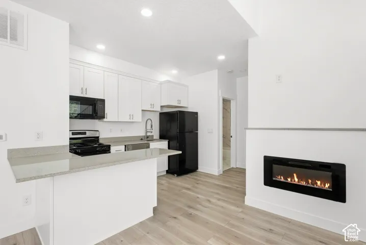Kitchen featuring white cabinetry, light-toned countertops, and black appliances