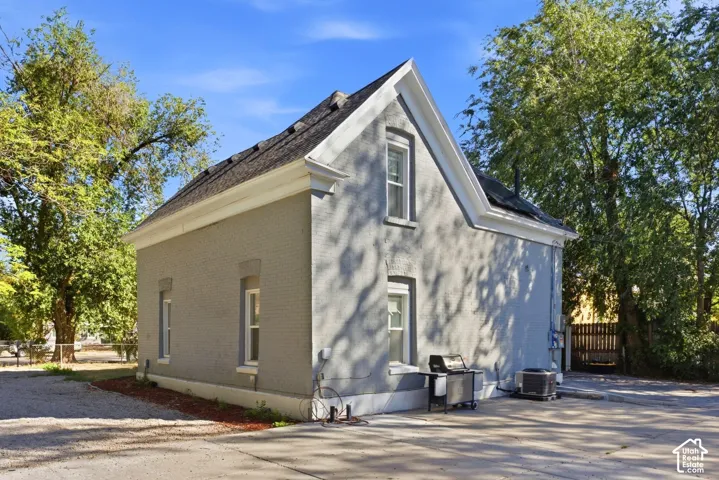 Gray brick exterior with white trim, gabled roofline, and multiple windows. Back of main house.