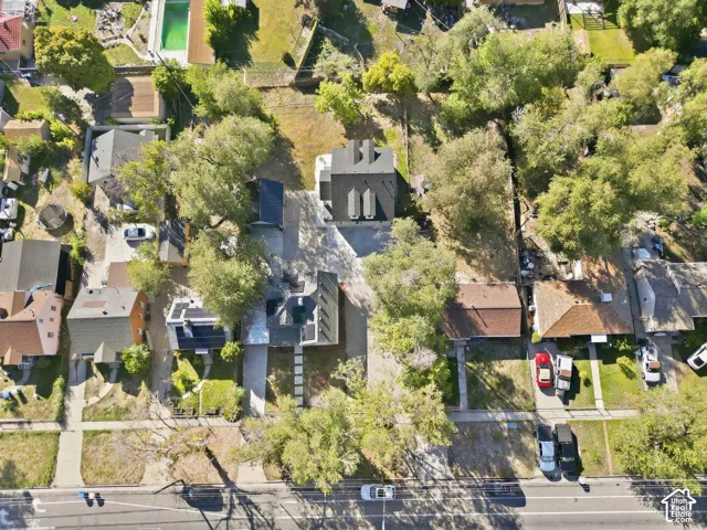Aerial view showcasing multiple residential properties, mature trees, and a street