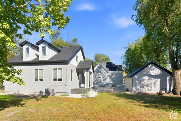 Stucco exterior with a dark shingle roof, multiple dormer windows, and a covered entry