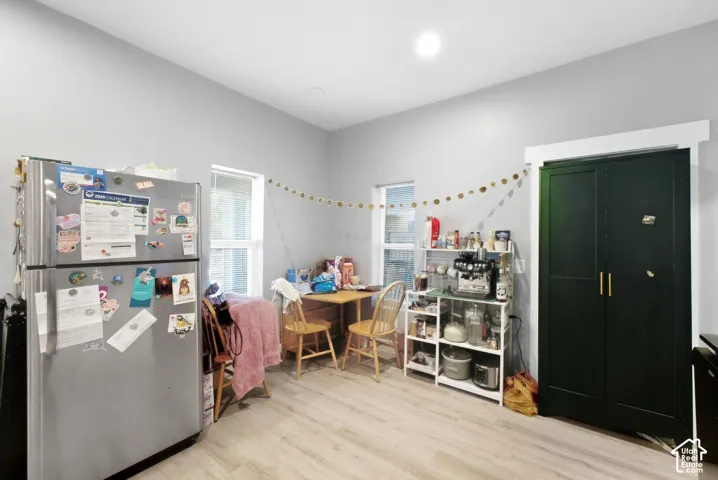 Light-toned wood-finish flooring, recessed lighting, and a dark-paneled built-in cabinet with brass hardware