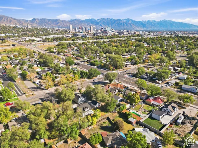 Expansive urban landscape featuring a cityscape, prominent mountain range, and established residential areas with mature trees