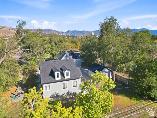 Gray-sided residence featuring a dark shingle roof and two dormer windows