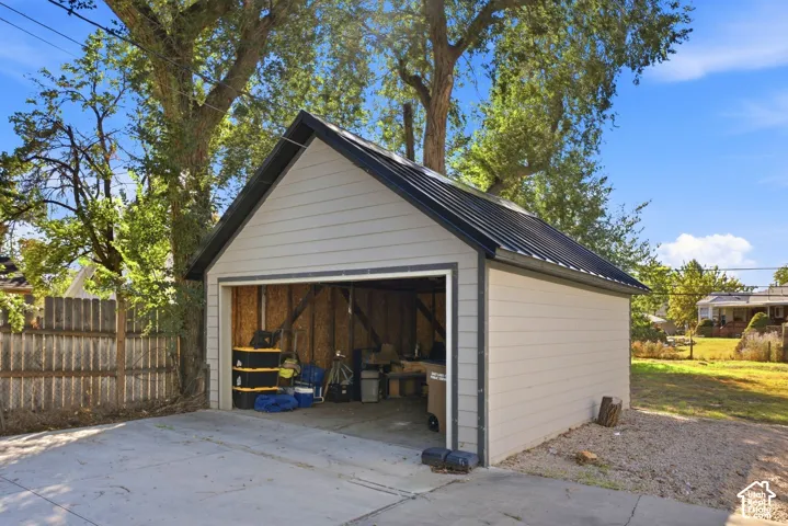 Detached garage with horizontal siding, a gabled roof, and a black metal roof