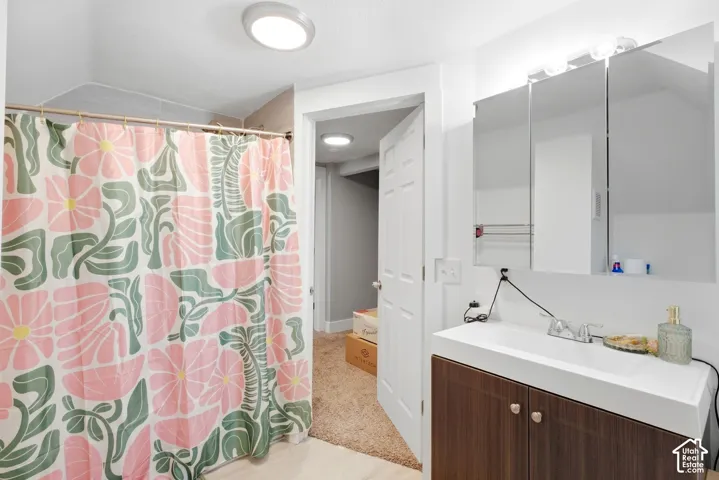 Vanity with integrated white sink, wood-finish cabinetry, and mirrored medicine cabinet