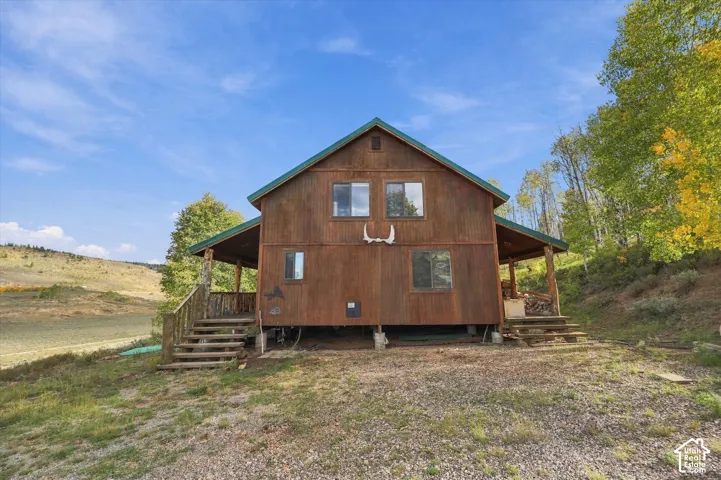 Gable-roof property featuring wood siding, an elevated foundation, and a covered front porch with log-style supports