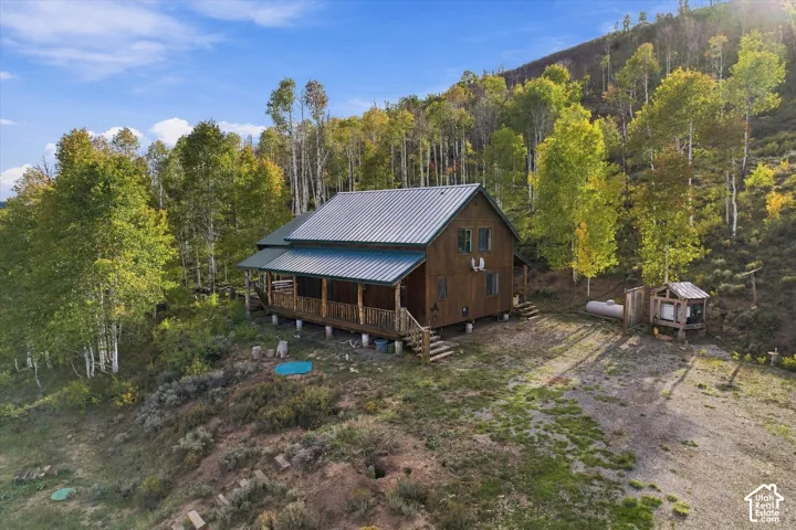Wood-sided cabin featuring a metal roof and an expansive covered porch with log supports