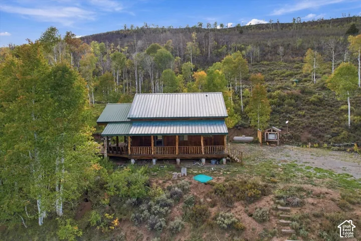 Wood-sided cabin featuring a metal roof and a full-length covered porch with wooden railings