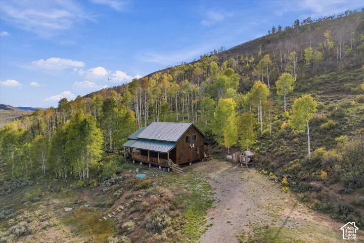 Wood-sided cabin featuring a covered porch, metal roof, and surrounding trees