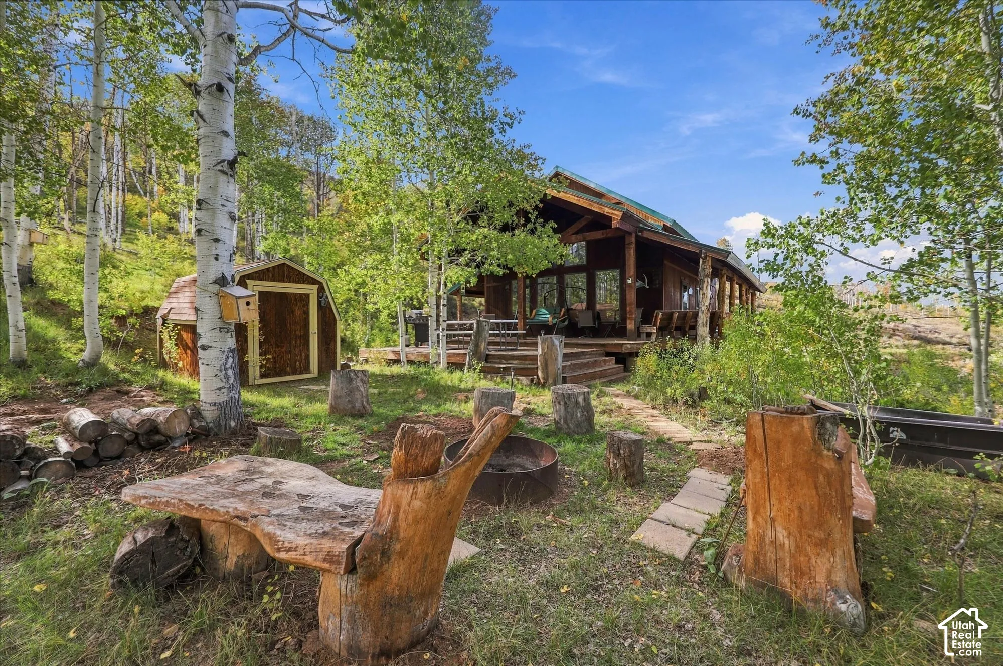 Wood-sided cabin with an expansive deck, featuring a gabled roofline and large windows