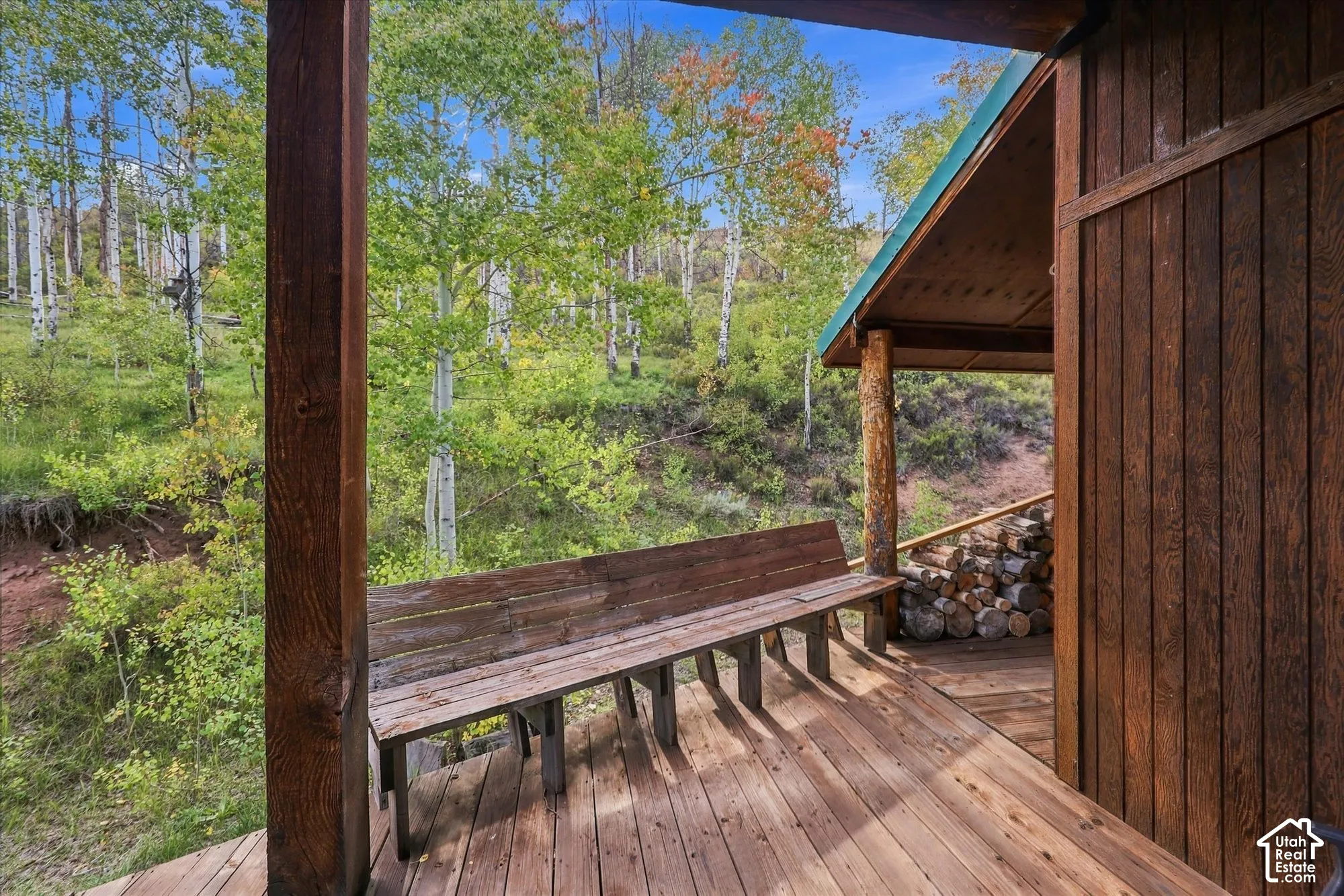 Covered deck with wood-finish flooring and timber beam construction overlooking mature forest landscape
