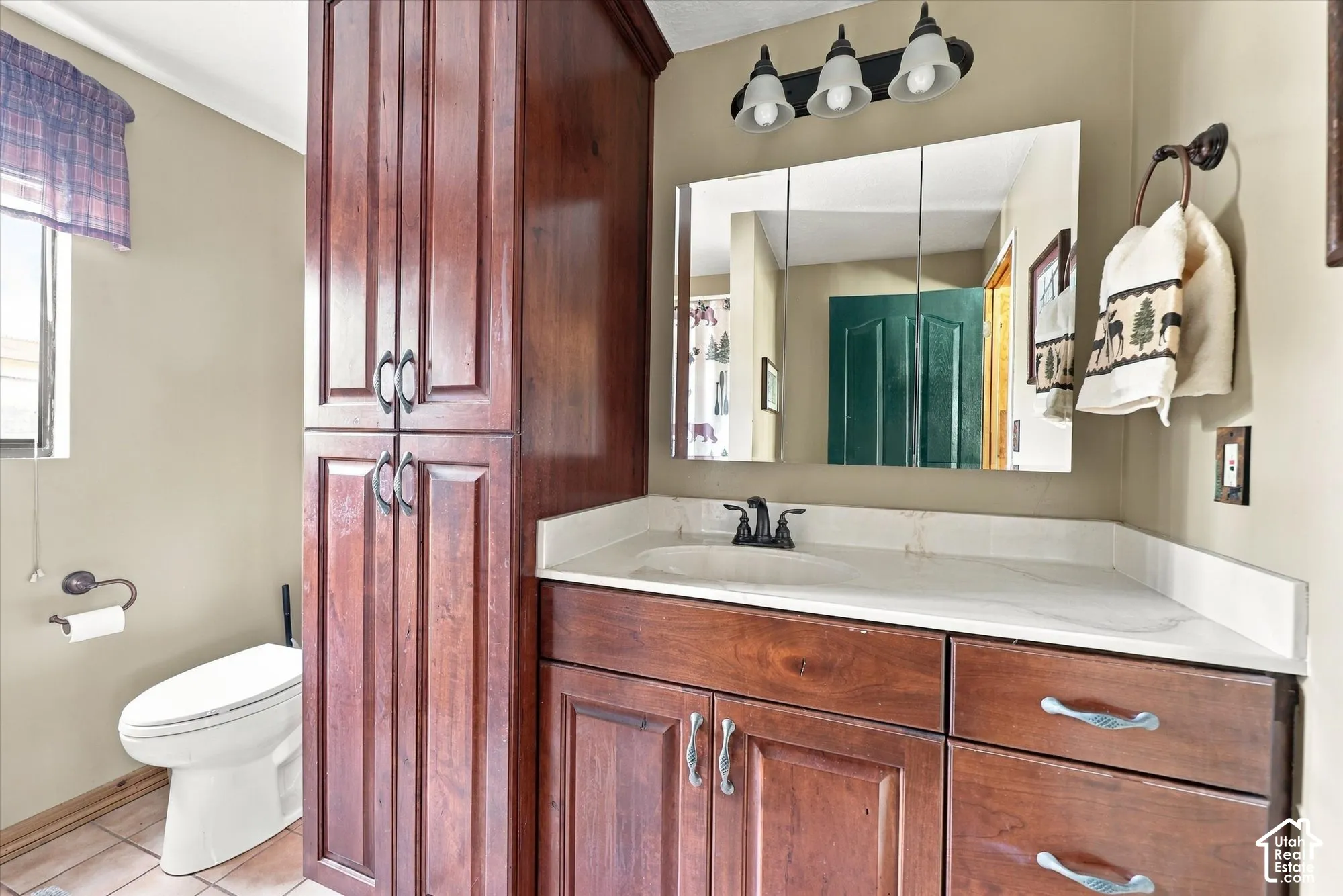 Built-in wood-finish cabinetry, integrated sink, wall-mounted medicine cabinet, modern vanity light fixture, and a single window